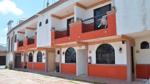 Un edificio de varios pisos con balcones, ventanas de arco y una planta baja con azulejos.