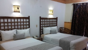 Dos camas individuales con cabeceros de madera, ropa de cama blanca y colchas estampadas.