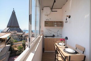 Ein schmaler Balkon mit Blick auf ein hohes Gebäude und die Skyline der Stadt.