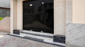 Une entrée d’immeuble avec une porte en verre, des marches et un mur en briques.