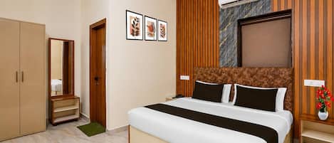 A hotel room with a bed, wardrobe, vanity, and a wall-mounted air conditioner.