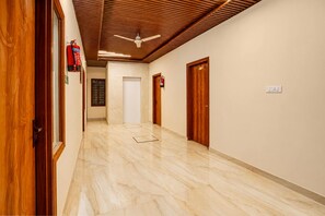 A hallway with wooden doors, a ceiling fan, and a fire extinguisher.
