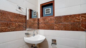 Une salle de bain avec un lavabo blanc, un miroir et un système de ventilation.