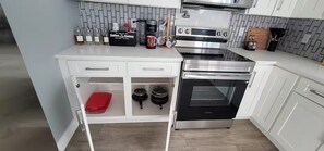 A kitchen with white cabinets, a built-in oven, a coffee maker, and a microwave. - Navigate Stays West Palm Beach 4BR Family Retreat (West Palm Beach)