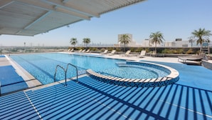 A swimming pool with a curved edge, lounge chairs, and a view of the city skyline. - Free Housekeeping Visits During Your Stay - Stayshort - Stunning Studio in JVT Sleeps 2 With Balcony (Dubai)