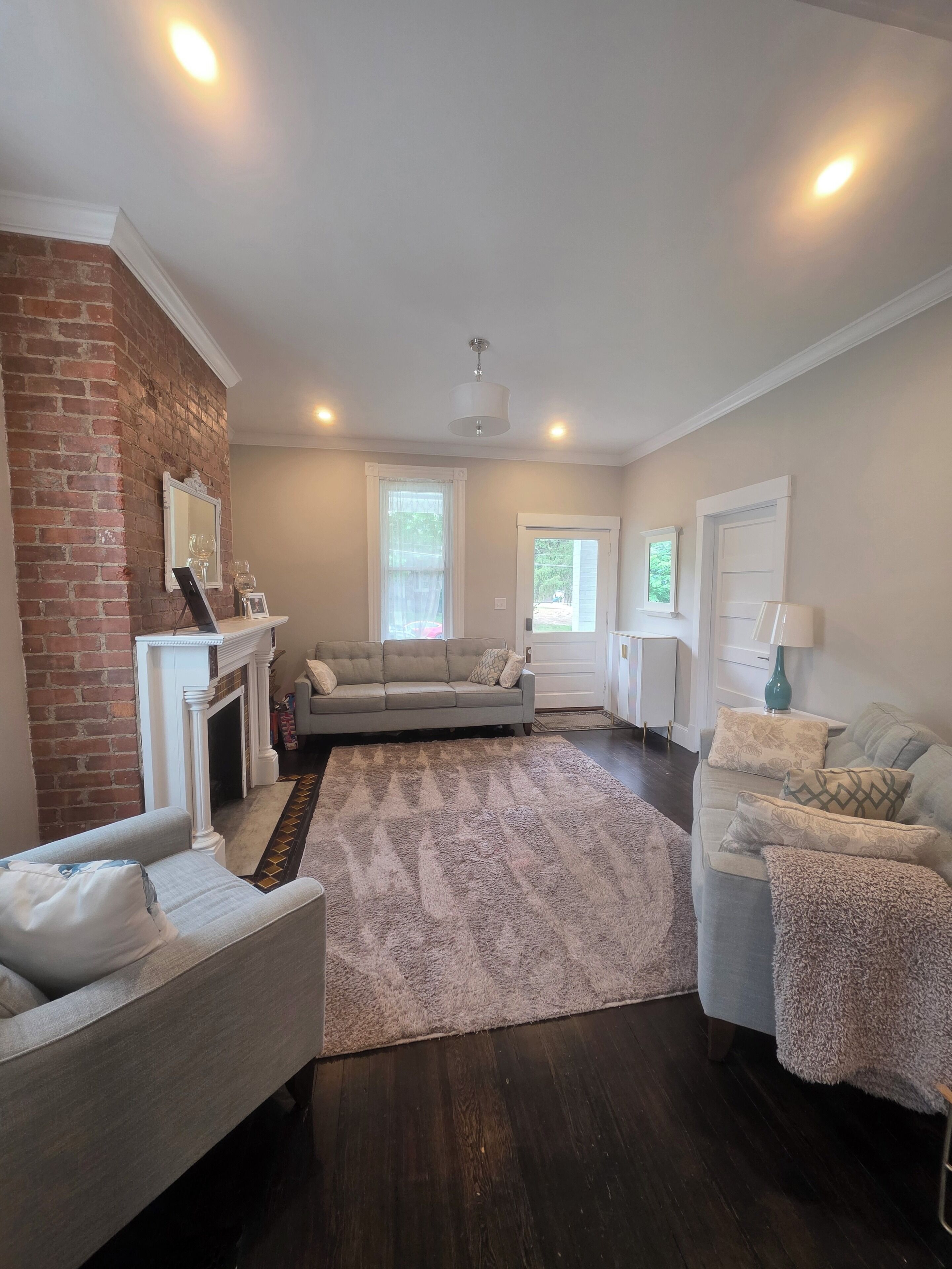 A living room with a fireplace, two sofas, a rug, and a brick wall.