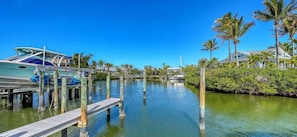 A marina with boats docked, a wooden pier, and a backdrop of palm trees and houses. - 3-bedroom condo in charming Siesta Key on intercostal and steps from beach (Siesta Key)