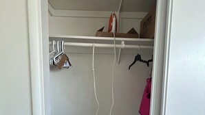 A small closet with hanging space, a shelf with a box, and a bag on the floor. - Peaceful 2-bedroom townhome with AC in charming Tucson (Tucson)