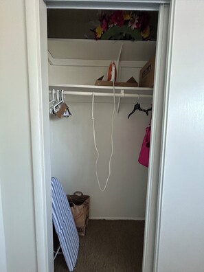 A small closet with hanging space, a shelf with a box, and a bag on the floor. - Peaceful 2-bedroom townhome with AC in charming Tucson (Tucson)