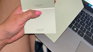A person holding several color swatches labeled with names and codes, with a laptop in the background. - Peaceful 2-bedroom townhome with AC in charming Tucson (Tucson)