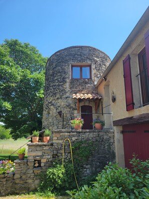 A stone house with a red door, a window, and potted plants on the balcony. - Unusual gîte for 2 people in a 17th century tower (Forcalquier)