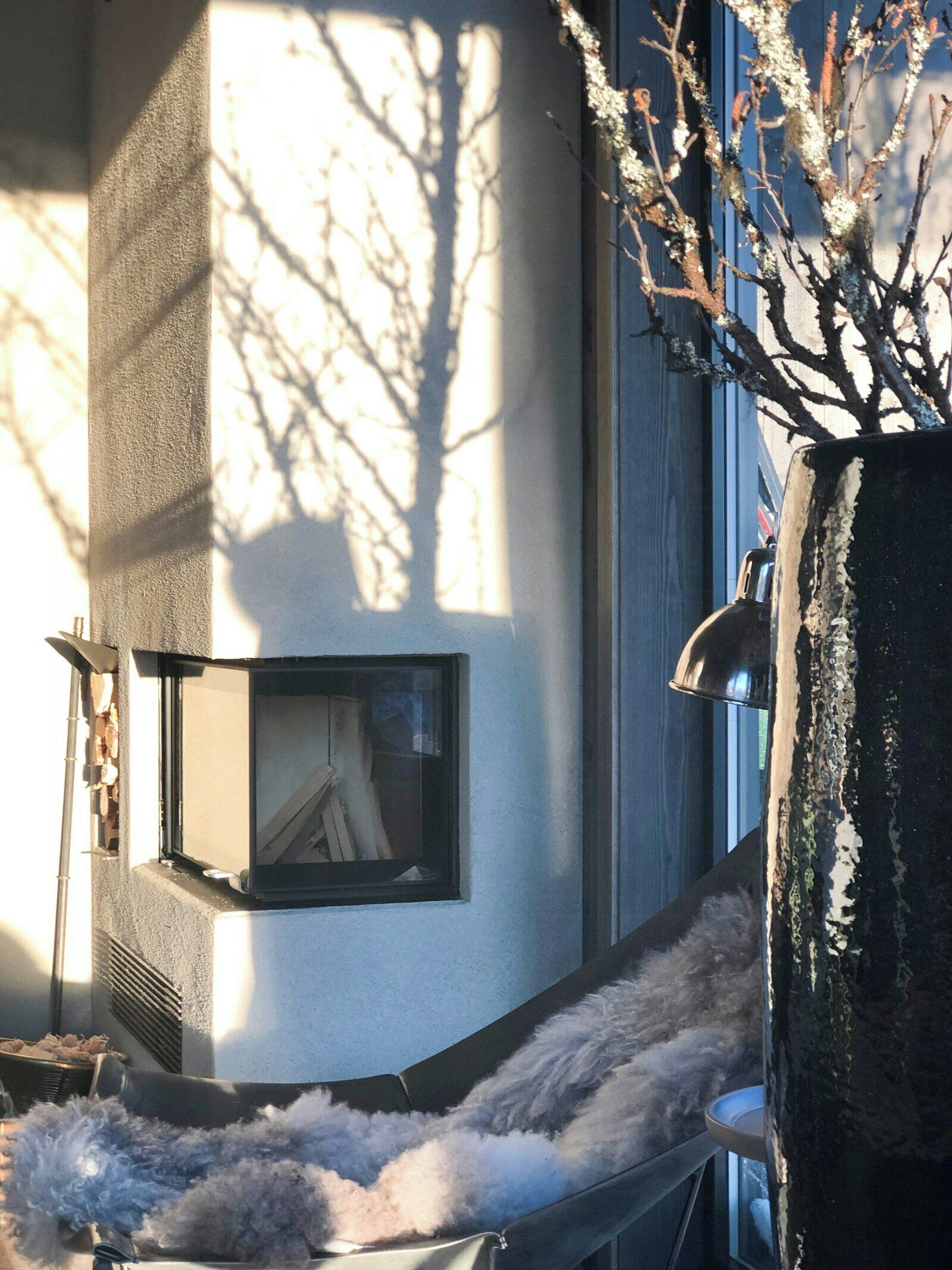 Un bâtiment doté d’une cheminée, une fenêtre offrant une vue dégagée et un arbre aux branches nues.