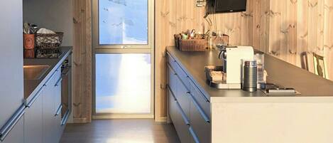 Une cuisine moderne avec des murs en bois, une grande fenêtre et des luminaires suspendus.