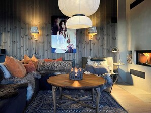 A cozy living room with a sofa, a wooden coffee table, and a fireplace.