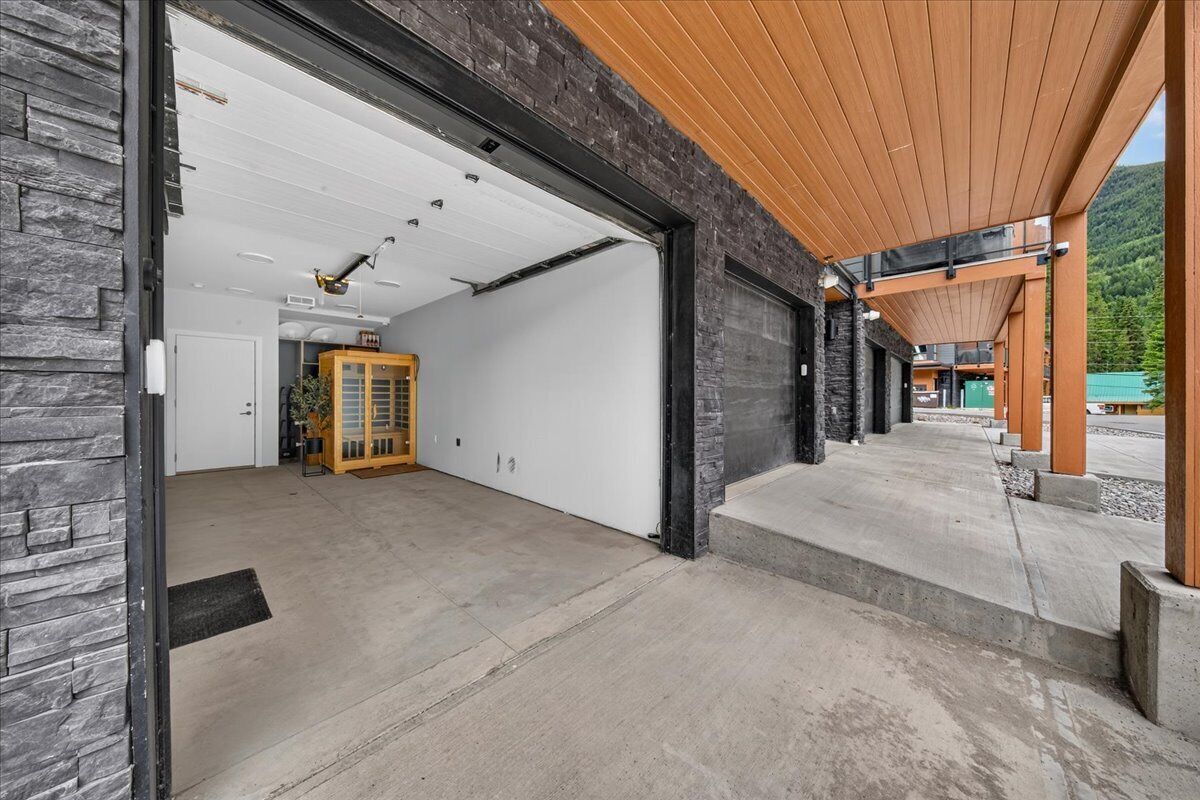 A modern garage with a concrete floor, a wooden ceiling, and a stone wall.