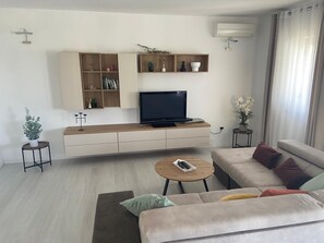 A modern living room with a sofa, a coffee table, a TV, and built-in shelves with decorative items.