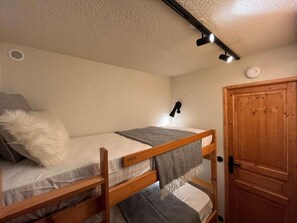A bunk bed with a headboard, a bedside lamp, and a wooden door. - 120 meters from the ski slopes, patio, parking, TV, ski locker, 19 m², Montchavin La Plagne (La Plagne)
