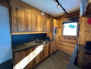 A kitchen with wooden cabinets, a sink, a toaster, and a window with a view. - Up to 10 meters from the ski slope, 2nd floor, terrace, parking, TV, 80 m², Peisey-Vallandry (Landry)