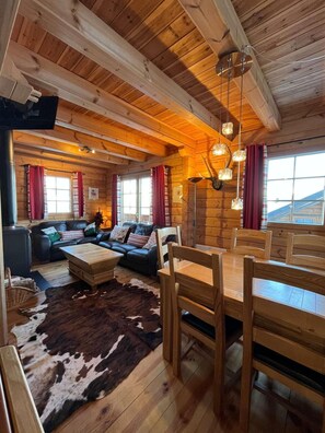 A log cabin interior with a dining area, sofa, and a cowhide rug. - Chalet, 5m from ski slopes, terrace, fireplace or stove, tv, 85m², Montchavin La Plagne (La Plagne)