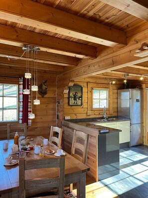 A wooden cabin interior with a dining area, kitchen, and a mounted deer head. - Chalet, 5m from ski slopes, terrace, fireplace or stove, tv, 85m², Montchavin La Plagne (La Plagne)