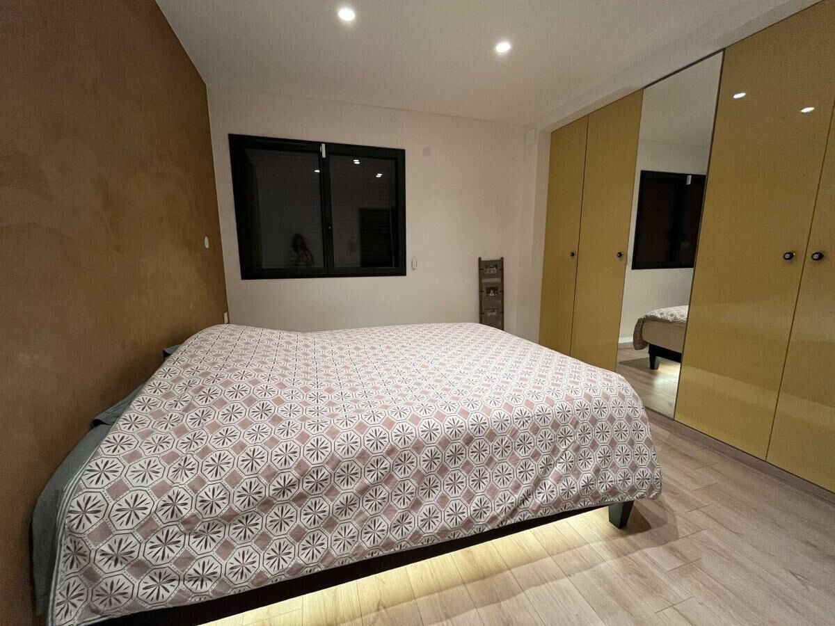 A bedroom with a bed, a wardrobe, a mirror, and a window.