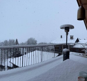 A snow-covered balcony with a metal railing, a street lamp, and a building with snow on its roof in the background. - 1st floor, sauna, terrace, fireplace or stove, tv, 180m², Montchavin La Plagne (Landry)