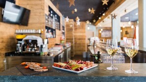 Een bar met houten inrichting, sterren decoraties aan het plafond, een toonbank met eten en drinken, en een televisiescherm op de achtergrond.