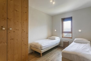A bedroom with two single beds, a wooden wardrobe, a window with a view, and recessed ceiling lights. - Wi-Fi, 50 meters from the resort center, valley view, patio, balcony, TV, 46–50 square meters, La Tzoumaz (La Tzoumaz)