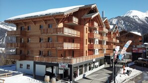 A multi-story wooden building with balconies, a bar, and a ski resort backdrop. - Wi-Fi, 50 meters from downtown, patio, balcony, TV, 72–91 square meters, La Tzoumaz (La Tzoumaz)