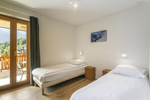 A bedroom with two beds, a wooden floor, a balcony with a view, and a painting on the wall. - Wi-Fi, up to 20 meters from the ski slope, patio, balcony, TV, 72–91 square meters, La Tzoumaz (La Tzoumaz)
