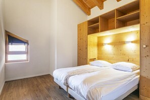 Ein Schlafzimmer mit einem hölzernen Kopfteil, einem Fenster und einem Bett mit weißer Bettwäsche.