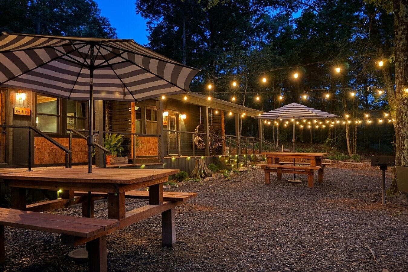 A rustic cabin with a covered patio, outdoor seating, and string lights.