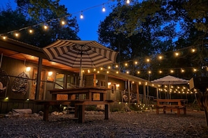 Eine rustikale Holzhütte mit Veranda, Lichterketten und Sitzgelegenheit im Freien.
