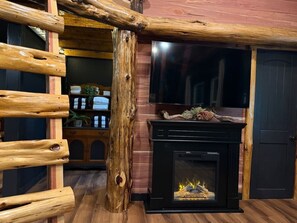 Ein rustikales Interieur mit Kamin, Holzscheiten und einer Leiter.
