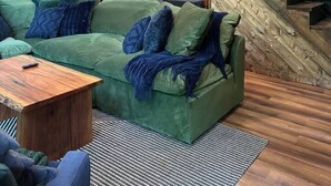 Ein modernes Wohnzimmer mit einem grünen Sofa, einem Holztisch und einer Treppe mit Holzgeländer.