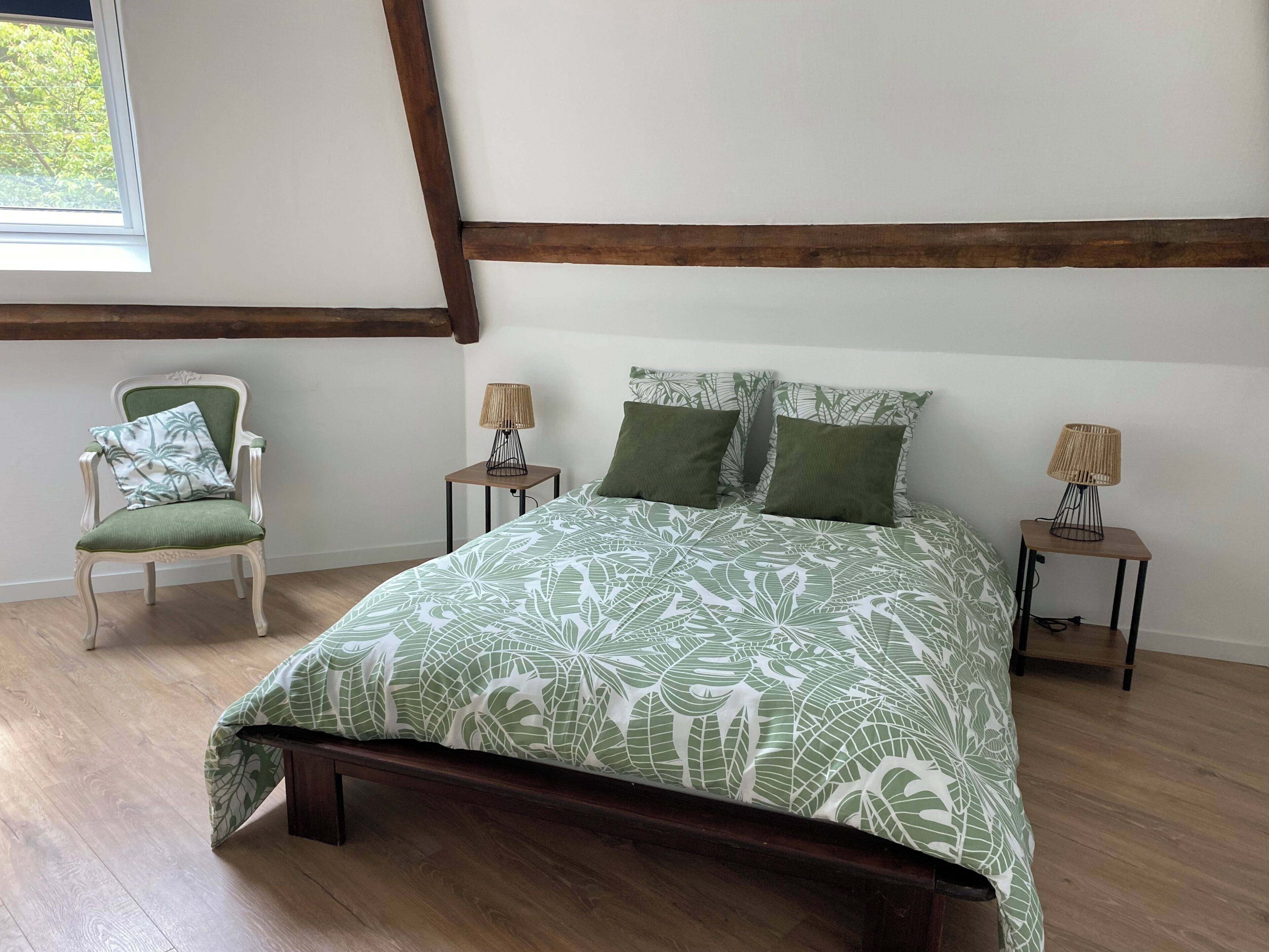 Une chambre à coucher avec un lit, une chaise, deux tables de chevet et une fenêtre.