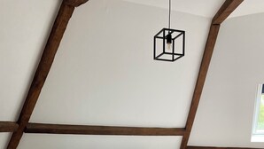 Ein Schlafzimmer mit Holzboden, einem Bett mit gestreifter Bettwäsche, einem Nachttisch mit Lampe und einer Pendelleuchte.