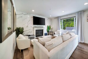 Un salon moderne avec une cheminée, un téléviseur à écran plat et un canapé.