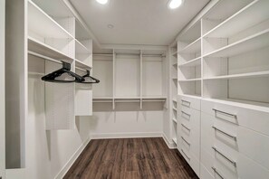 A walk-in closet with white shelving and drawers, a wooden floor, and two hanging clothes racks. - The Stagg Lane Retreat (Los Angeles)