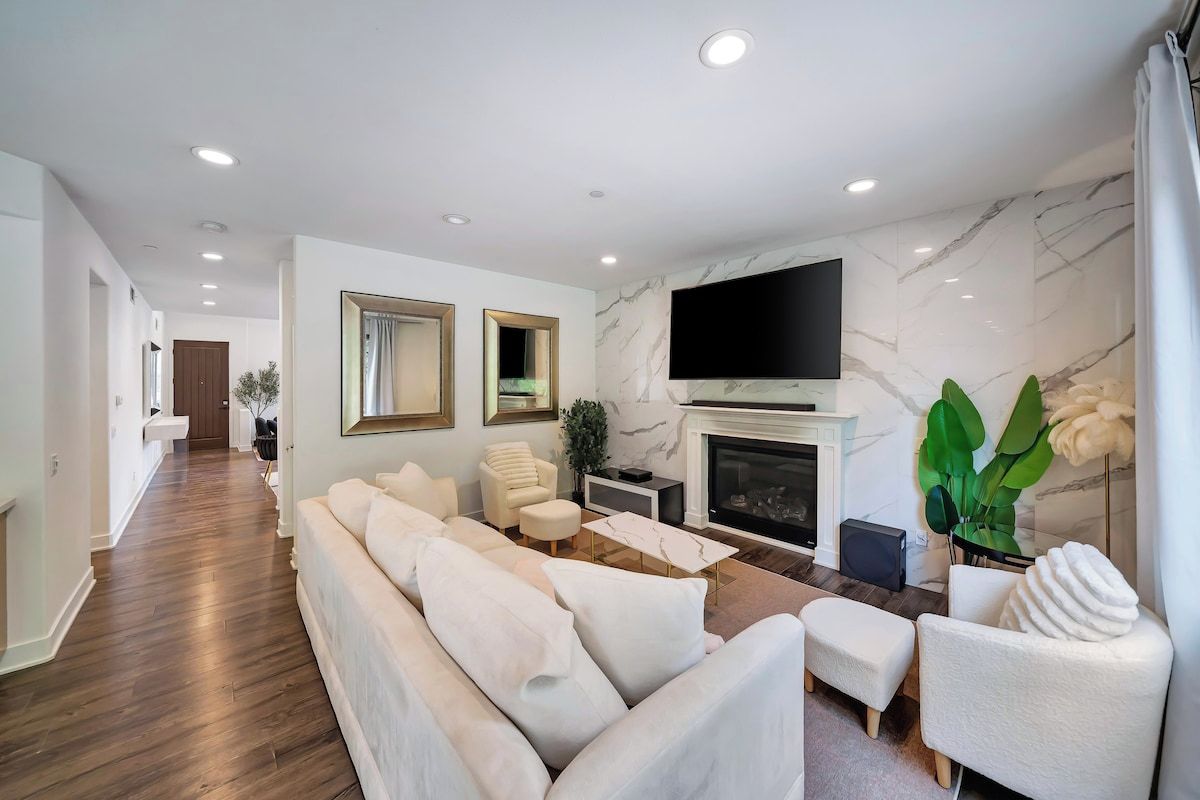 A modern living room with a fireplace, a sofa set, and a flat-screen TV mounted above it.