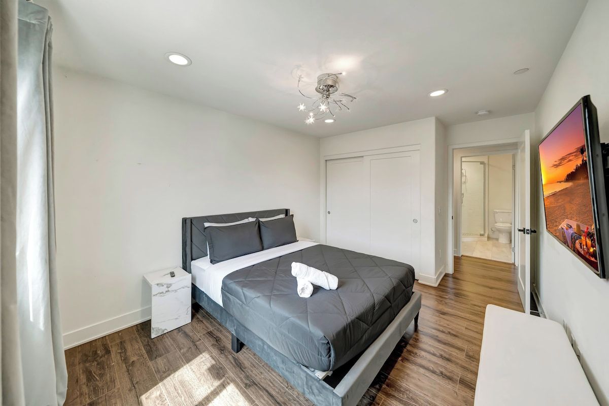 A modern bedroom with a bed, bedside table, and a ceiling light fixture.