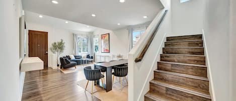 Un interior moderno con una escalera, un comedor y una sala de estar.