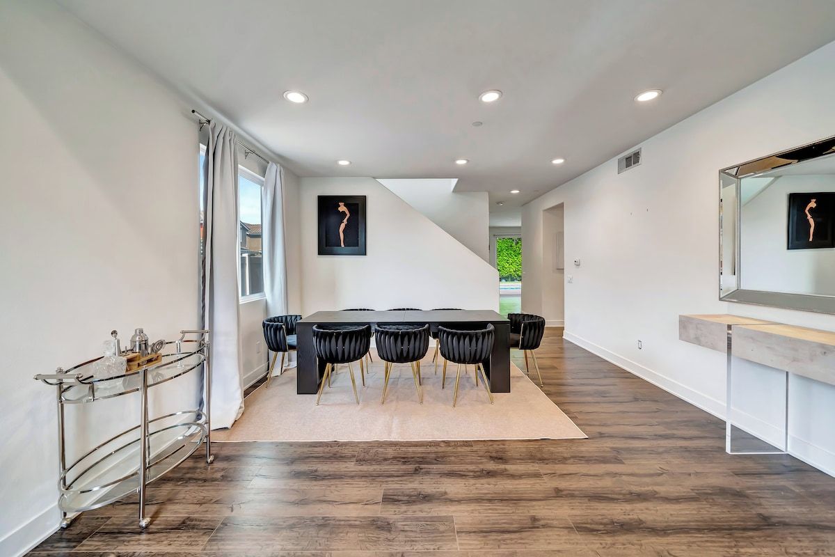 Un espace de restauration moderne avec une longue table, des chaises noires et un chariot en verre.