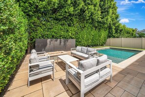 An outdoor patio with a pool, white furniture, and a hedge wall. - The Stagg Lane Retreat (Los Angeles)
