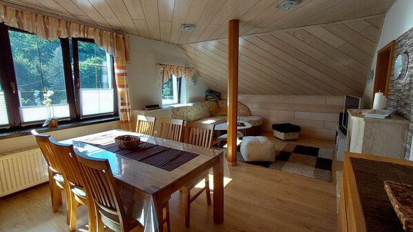 A cozy attic room with a dining table, chairs, a sofa, and a fireplace.