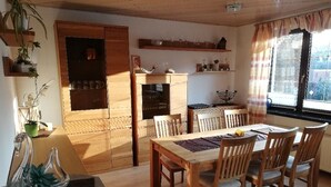 Ein Essbereich mit Holztisch und Stühlen, einem eingebauten Ofen und einem Fenster mit Vorhängen.