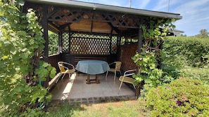 A covered patio with a table and chairs, surrounded by greenery. - Comfortable vacation apartment in the spa town of Bad-Schlema - for well-being & relaxation (Aue-Bad Schlema)