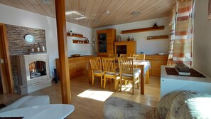 A cozy living area with a fireplace, wooden furniture, and a dining table.