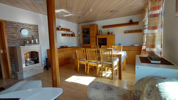 A cozy living area with a fireplace, wooden furniture, and a dining table.