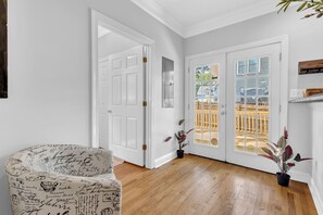 Ein Zimmer mit Holzboden, einer weißen Tür, einem weißen Stuhl und einer Topfpflanze.